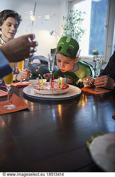 Little boy with costume blowing the candles on cake