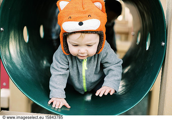 Little boy with fox hat playing at the playground.