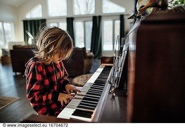 Little boy with messy hair playing the piano