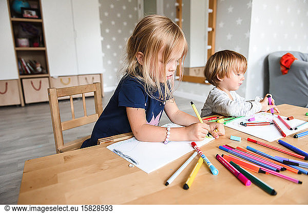 Little boy with sister drawing with felt-tip pens