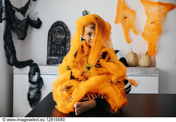 Little boy wrapped in orange spider web at Halloween