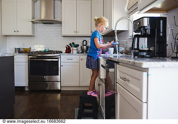 Little girl at sink washing dishes