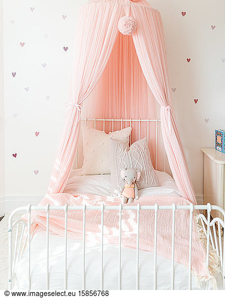 little girl bed with stuffed animal and pink canopy