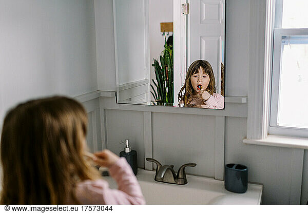 Little girl brushing her teeth independently in the bathroom