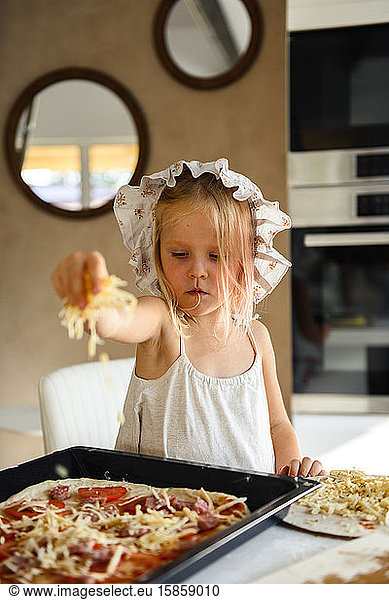 Little girl cooking pizza in the kitchen