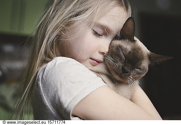 Little girl cuddling with her Burma cat
