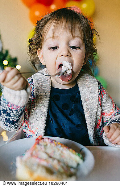 Little girl eating a piece of birthday cake