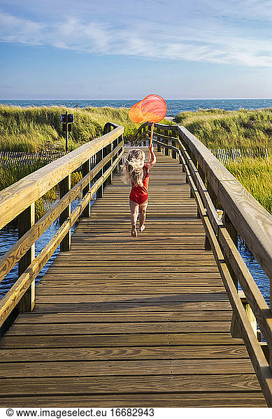 Little Girl from Behind Running On Bridge to Beach with Red FishingNet