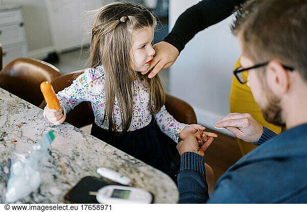 little girl getting poked in finger to read blood sugar levels