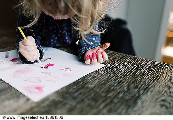 Little girl having a ball painting with her mother.