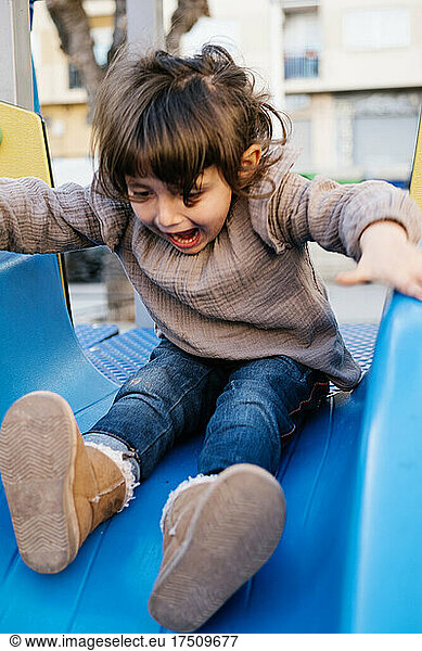 Little girl having fun on a playgound slide