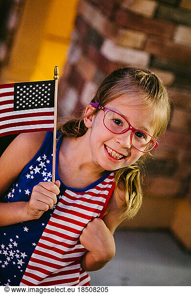 Little girl holding an American flag with red  white and blue