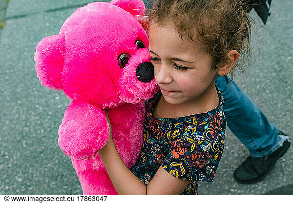 Little girl holding pink stuffed teddy bear