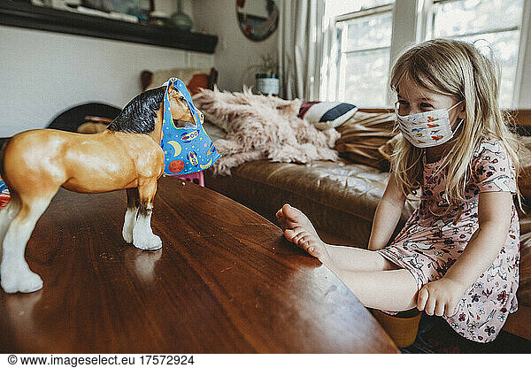 Little girl in mask playing covid-19
