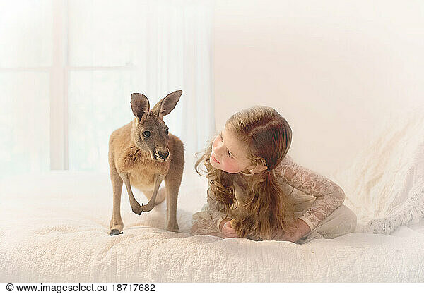 little girl in pigtails on a bed with a kangaroo
