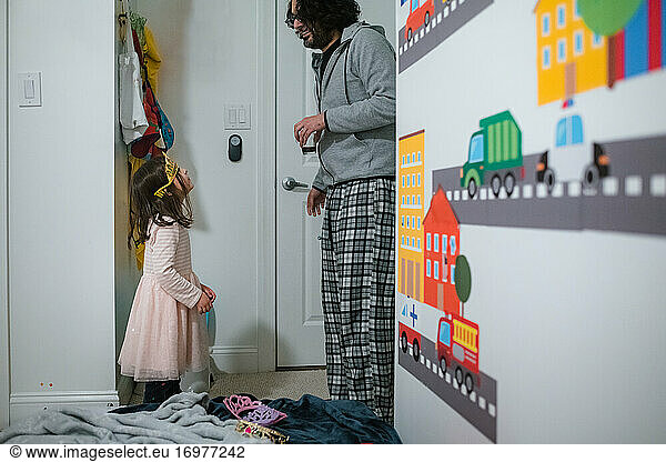 Little girl in tiara looking up at dad in domestic kids bedroom