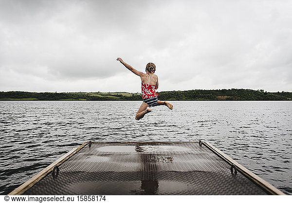 Little Girl Jumps off Dock into Lake on a Cloudy Summer Day