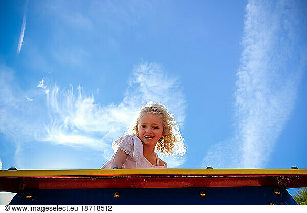 little girl looking down at camera from above at playground climbing