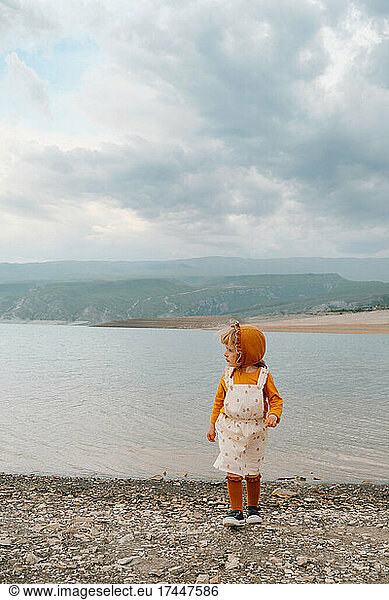 little girl looking towards the mountain lake