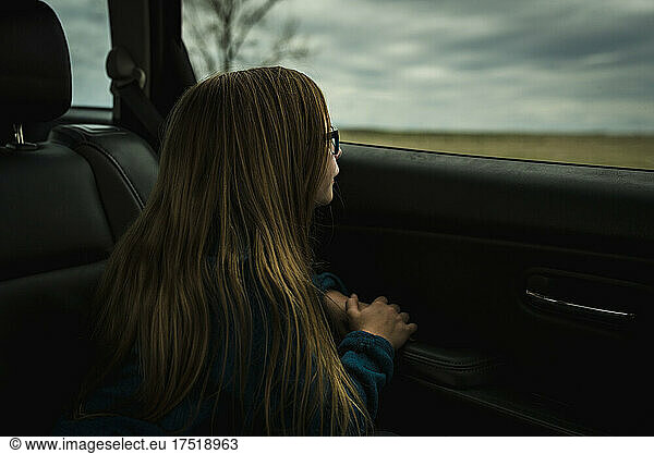 Little Girl looks out window of car on a road trip