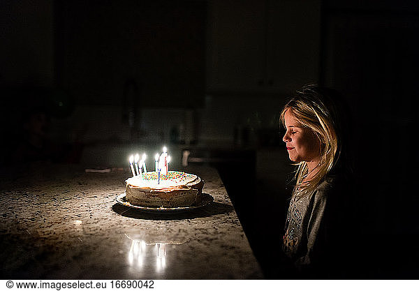 Little girl making a wish before blowing out birthday candles