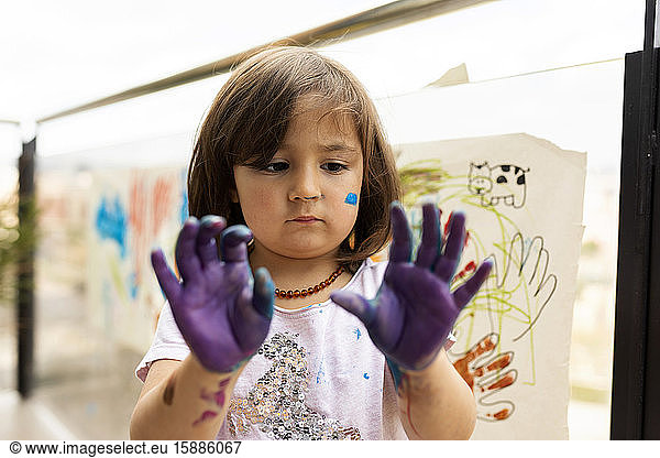 Little girl messing around with her painted hands
