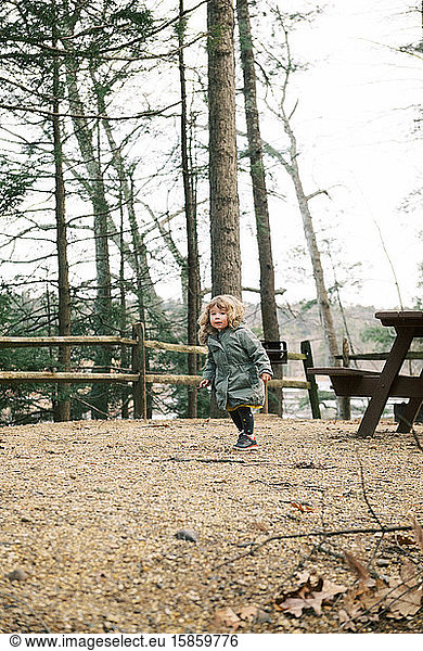 Little girl on a wintery walk through a park with her family.
