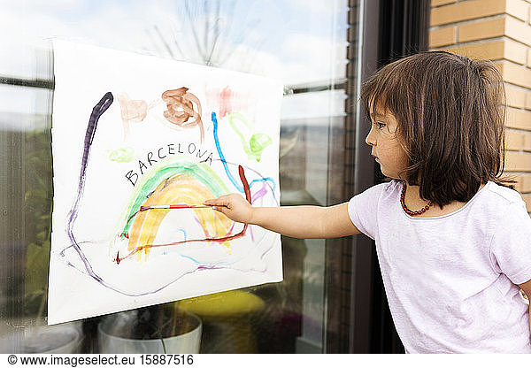 little girl painting a picture on the window
