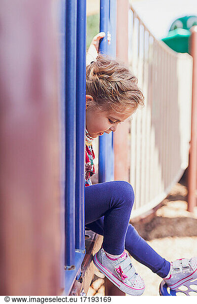 Little girl playing alone in a public playground.