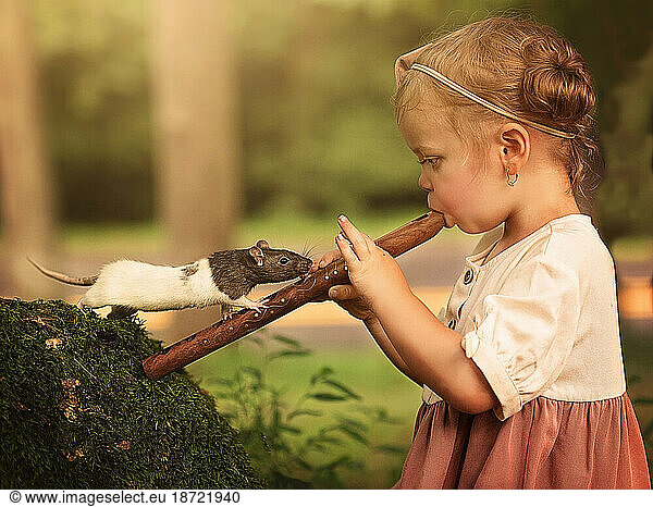 little girl playing recorder outside with a rat or mouse watching her