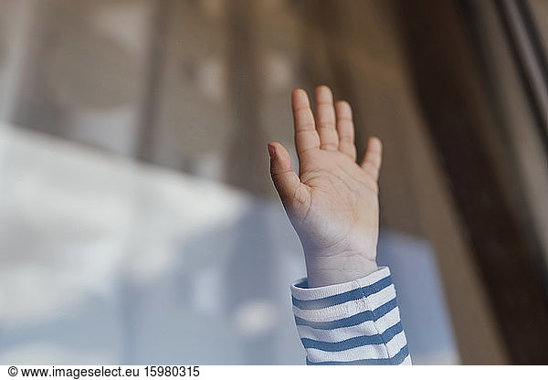 Little girl's hand behind windowpane