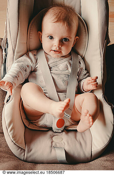 little girl sitting in a car seat looking at the camera
