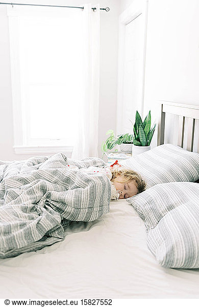 Little girl sleeping in her parent's bed.