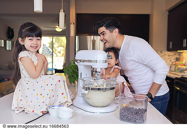 Little girl smiling at the camera and dad looking proud  family baking