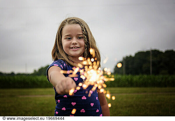 Little girl smiling with sparkler on Fourth of July