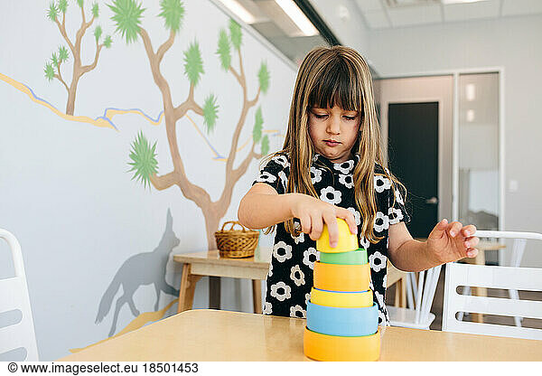 Little girl stacks cylinders in an educational facility