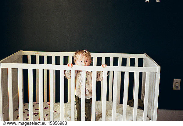 Little girl standing up in her crib.