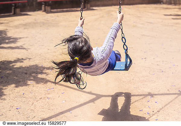 Little girl swinging in playground