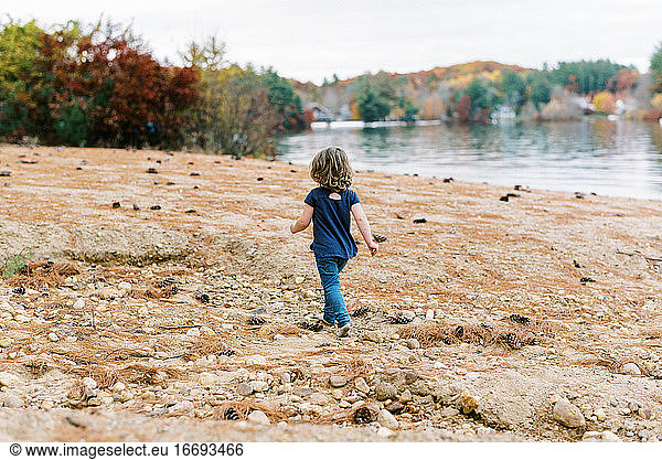 Little girl walking on a rocky beach in her socks