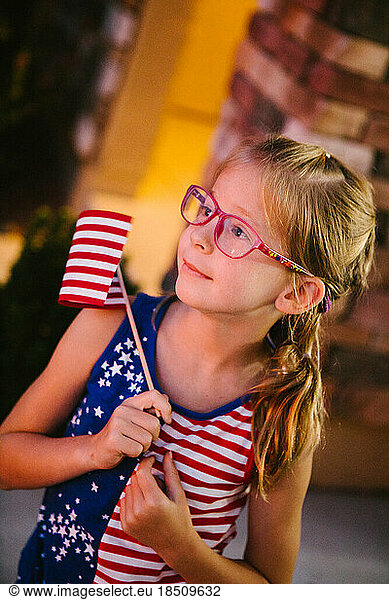 Little girl with glasses holding a American flag in her hands