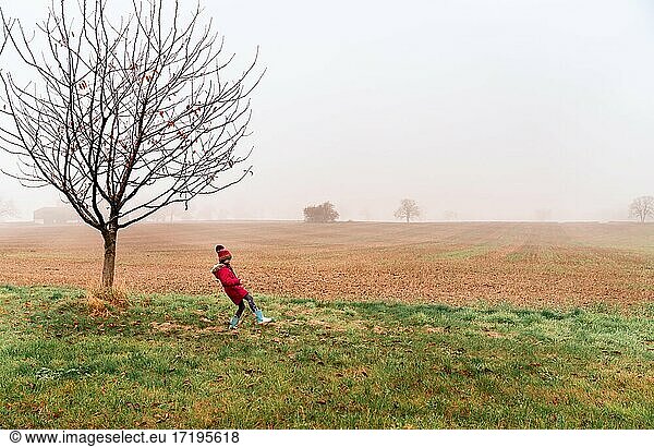 Little girl with read coat on a foggy morning in england countryside