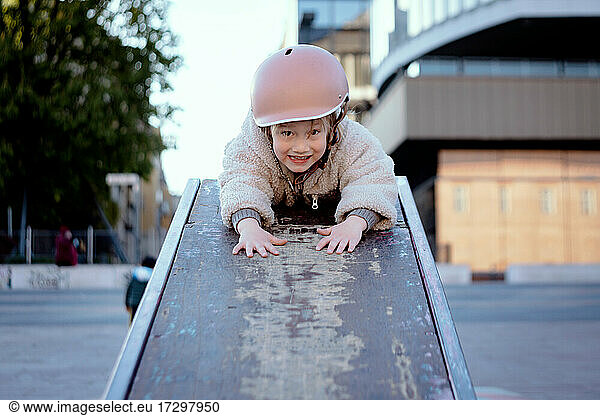 Little girl 4 years old at the skate park smiling in a helmet