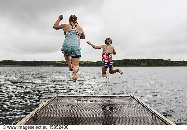 Little Girls Jump off Dock into Lake on a Cloudy Summer Day
