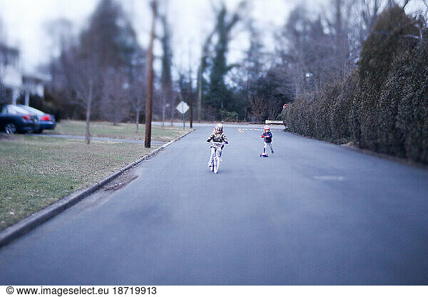 little girls playing outside riding bike and scooter on street