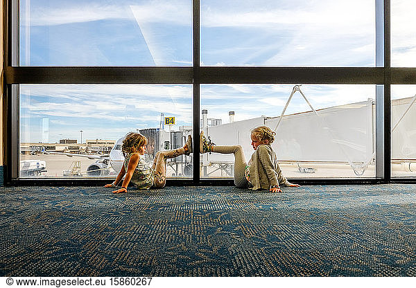 little girls sitting on ground looking in airport terminal