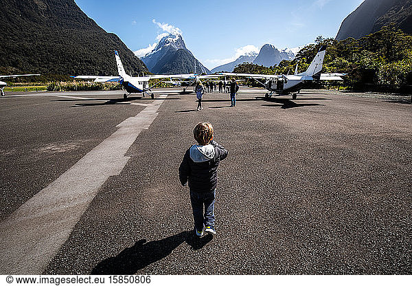 Little kid at airport runway with mountains in the back