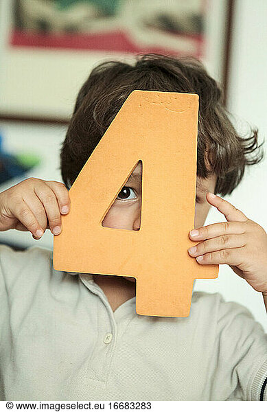 little kid holding a foam number on his hands