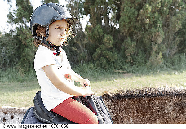 Little kid riding horse in nature