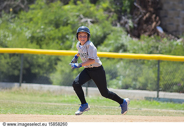 Little League baseball player running with big smile