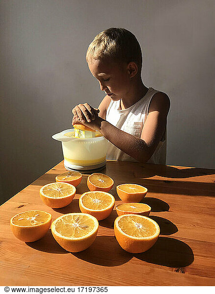 Little mum's helper. Little boy makes an orange juice in the kitchen.